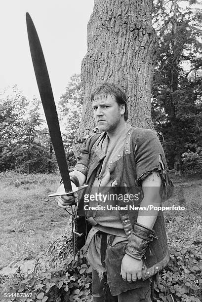 English actor Ray Winstone pictured holding a sword, dressed in character as Will Scarlet from the television adventure series 'Robin of Sherwood' in...