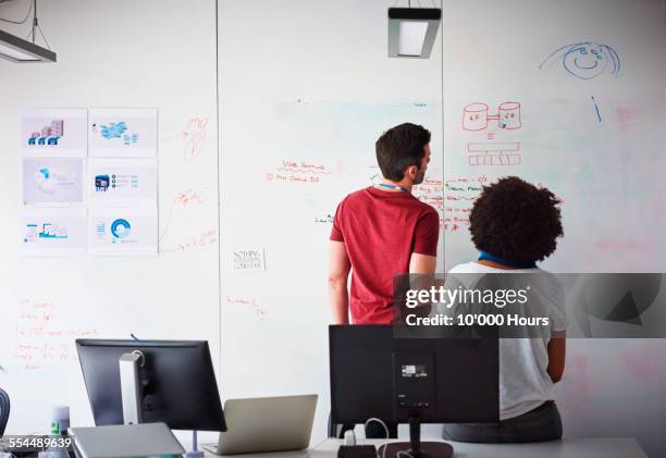 coworkers brainstorming in a start-up office - whiteboard stock pictures, royalty-free photos & images