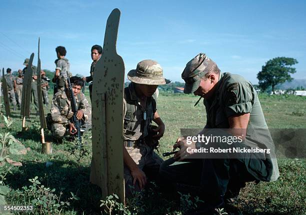 One of 55 U.S. Army trainers, R, points out a bullet grouping to a soldier during target practice in El Salvador's Army August, 1984 in San Miguel,...