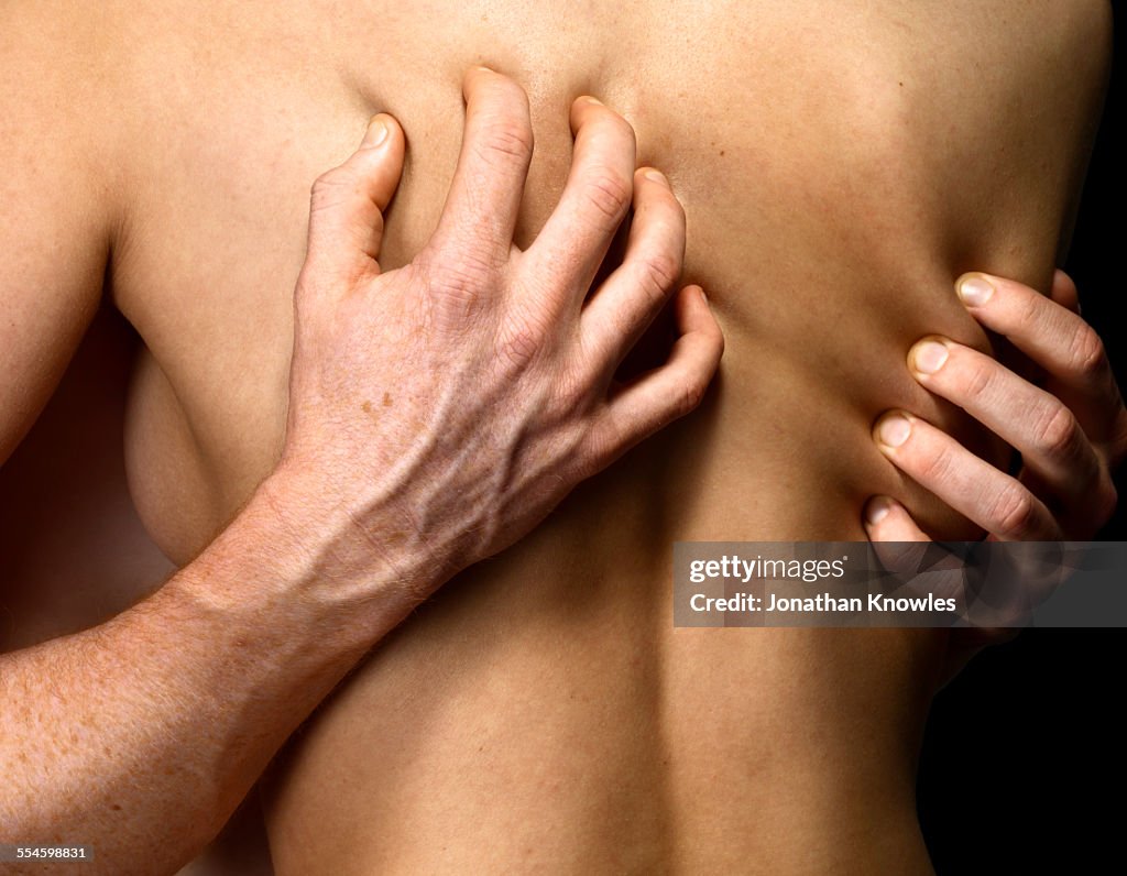 Man's hands gripping woman's back, close up