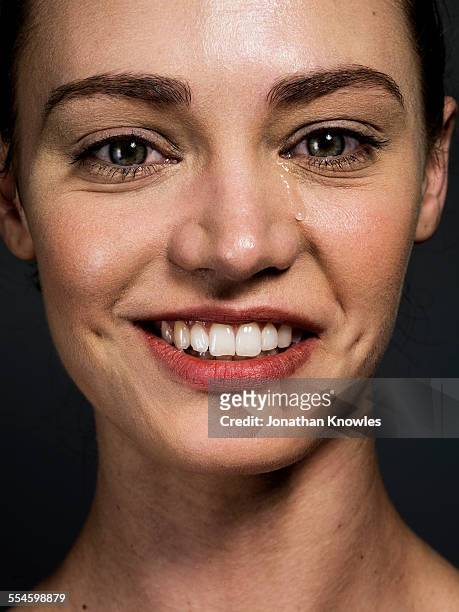woman smiling with a tear running down her face - teardrop stock-fotos und bilder