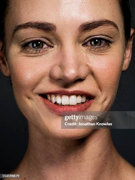 woman smiling with a tear running down her face - tear face photos et images de collection