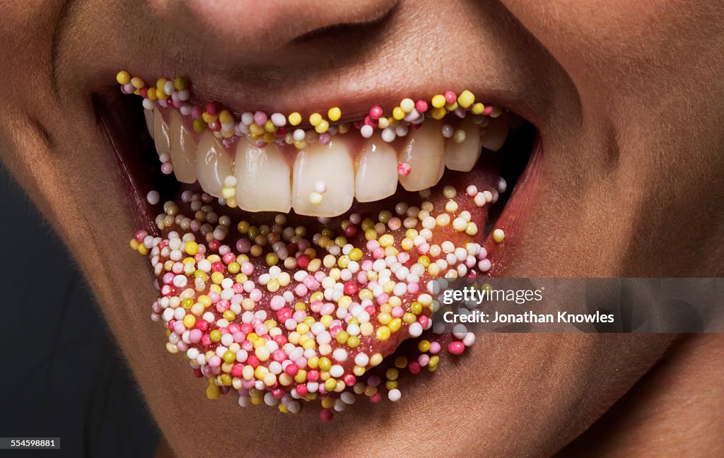 Female' tongue and lips covered in sugar sprinkles