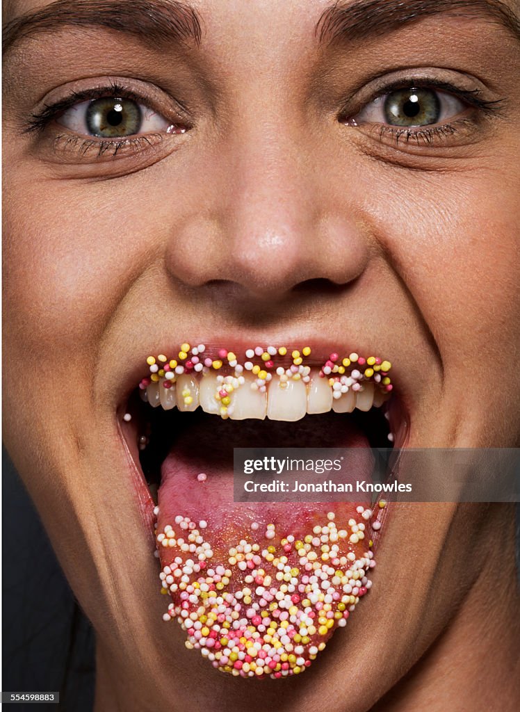 Woman's tounge and lips coated with colorful candy