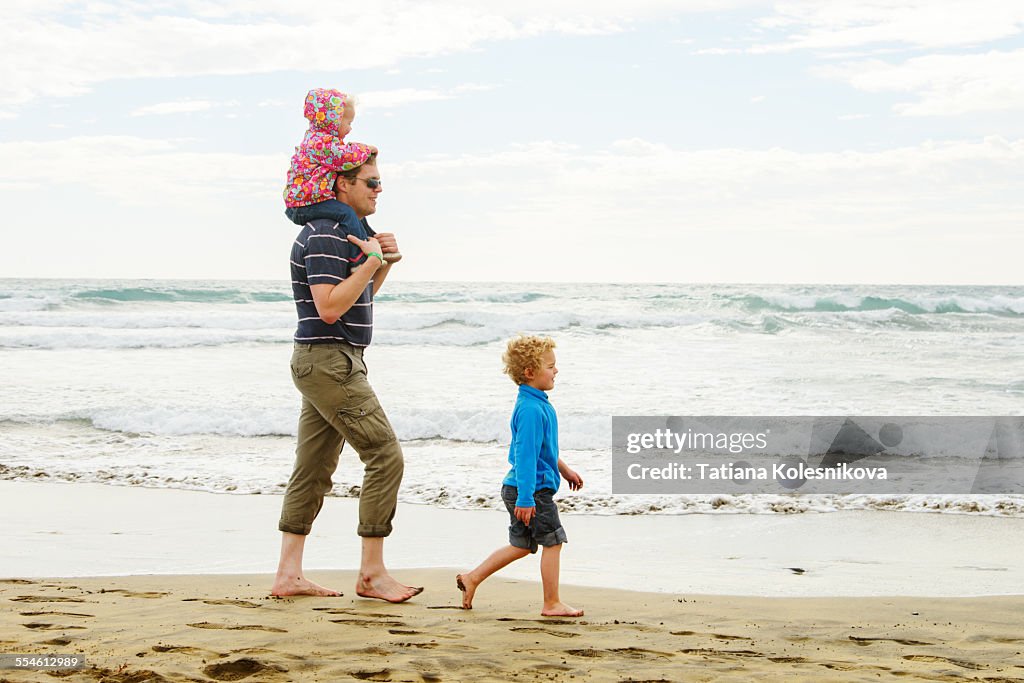 Father and two children alking by the sea