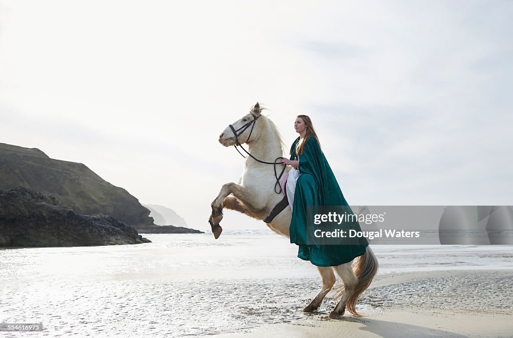 Woman on rearing horse at beach