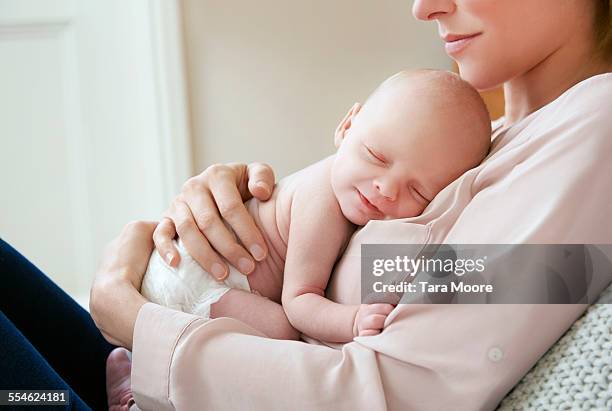 baby sleeping on mother's chest - mum sitting down with baby stockfoto's en -beelden