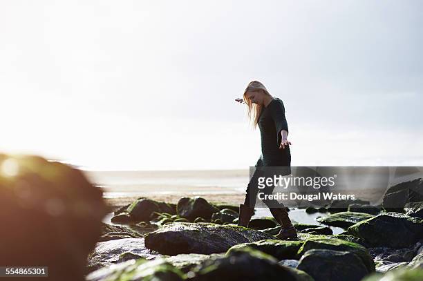 woman walking over coastal rocks. - balance stone stock pictures, royalty-free photos & images