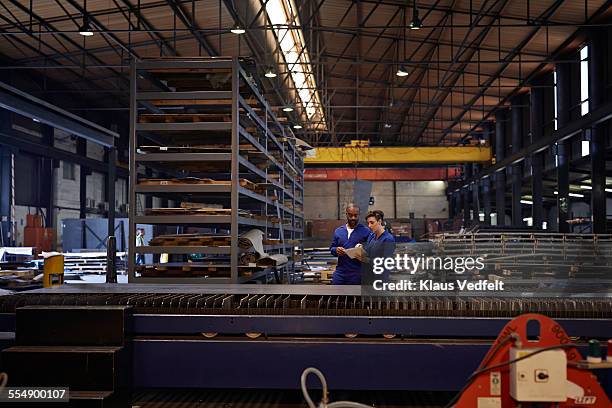 female & male steel workers looking at tablet - metallic look stock pictures, royalty-free photos & images
