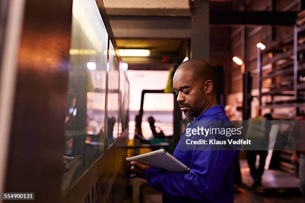 steel worker looking at tablet next to big machine - factory ipad stock pictures, royalty-free photos & images