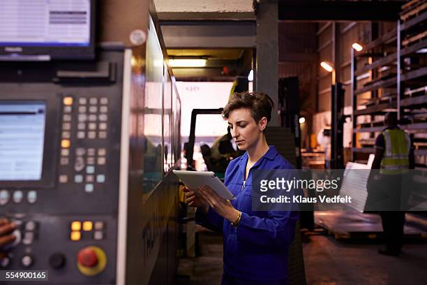 female steel worker holding tablet inside factory - femminilità foto e immagini stock