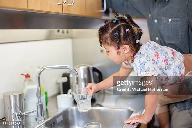 young girl filling glass of water at tap - girl filling water glass stock pictures, royalty-free photos & images