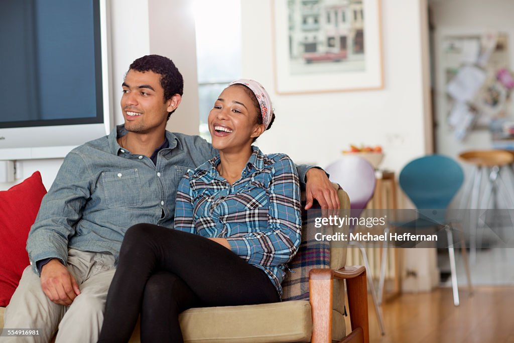 Mixed race couple smiling on sofa