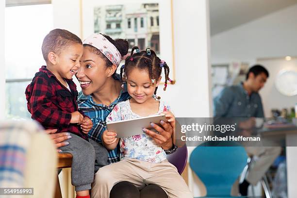 mother, son and daughter having fun with tablet - mixed race family photos et images de collection