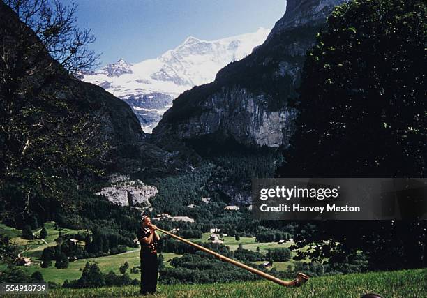 Man playing an alphorn or alpine horn in Grindelwald, Switzerland, circa 1965.