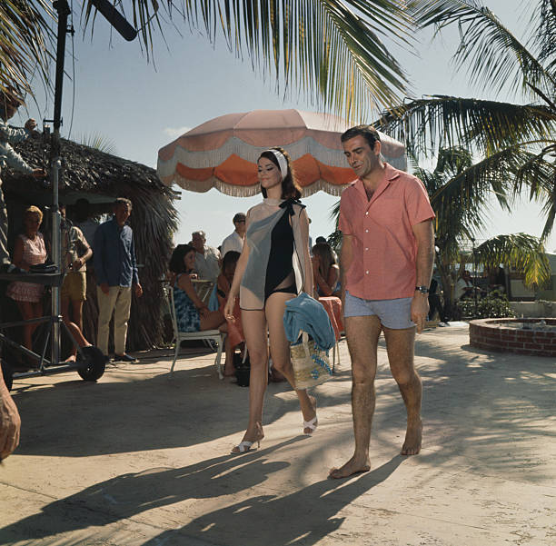 Scottish actor Sean Connery pictured walking with French actress Claudine Auger during filming of the James Bond film 'Thunderball' at a beach resort...