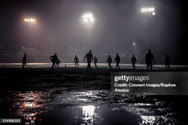 group of people playing rugby on floodlit pitch at night - soccer field at night stock pictures, royalty-free photos & images