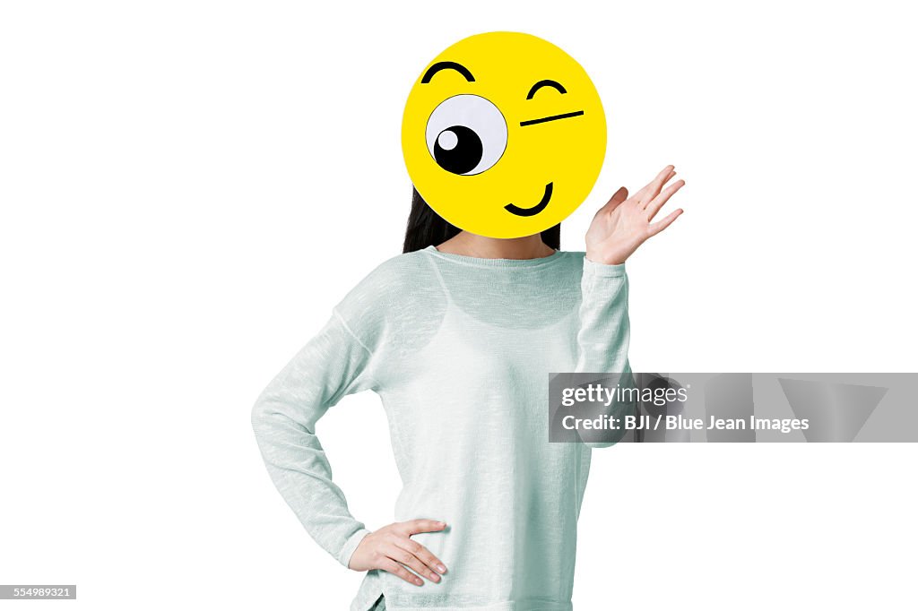 Young woman with a winking emoticon face in front of her face