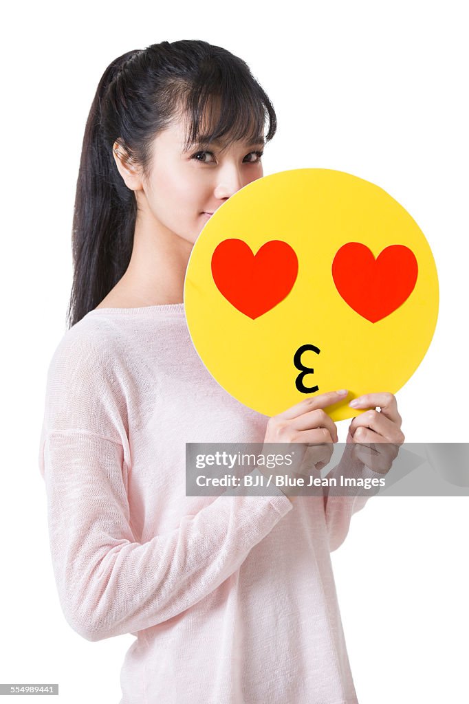 Young woman holding a romantic emoticon face