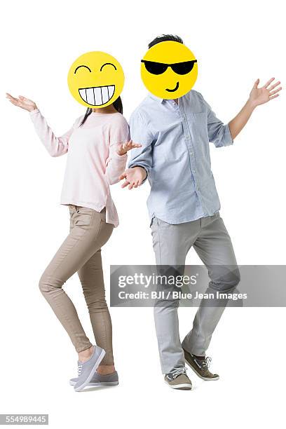 young couple with cartoon emoticon faces in front of their faces - human attribute fotografías e imágenes de stock