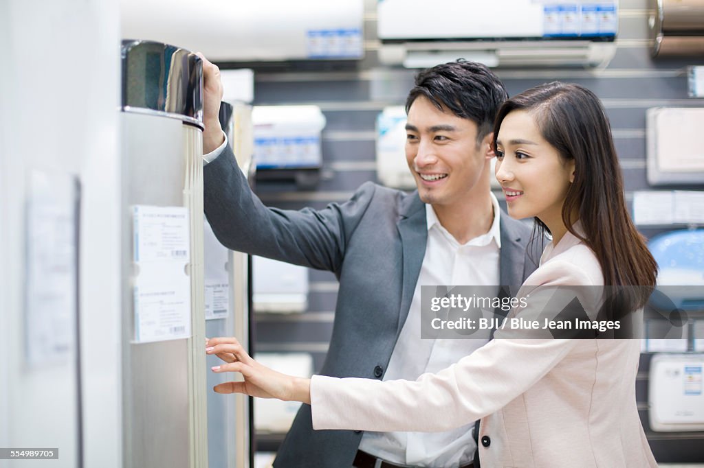 Young couple buying air conditioner in electronics store