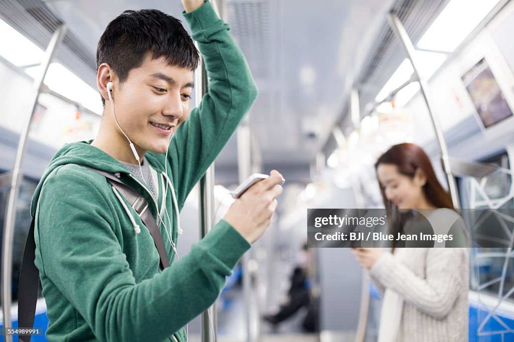 Young man listening to music in subway