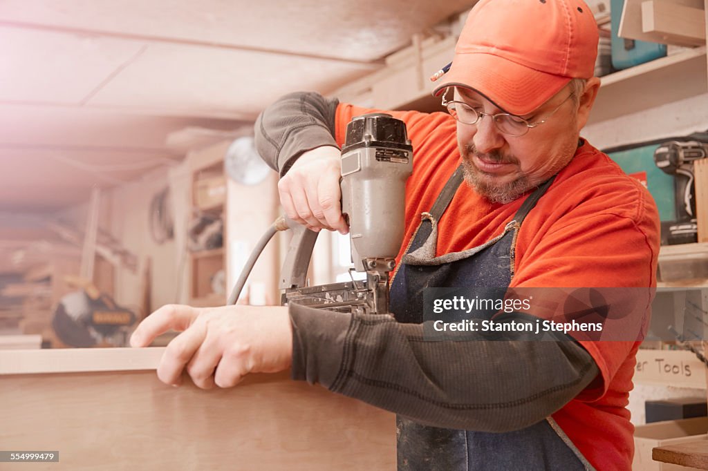 Cabinet maker using electric drill in workshop