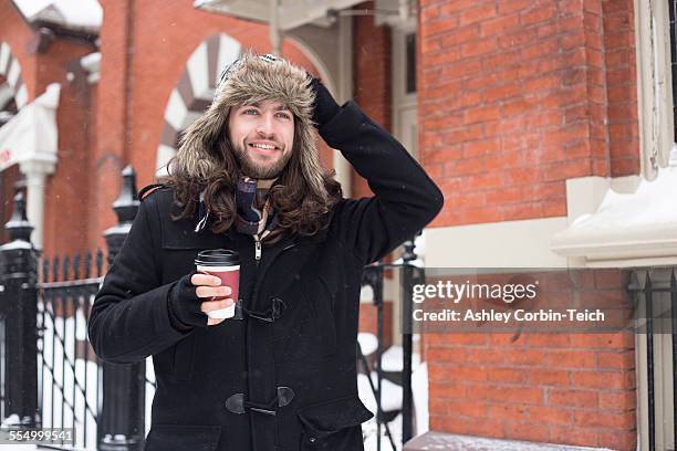 young man strolling along street drinking takeaway coffee - man mid 20s warm stock pictures, royalty-free photos & images