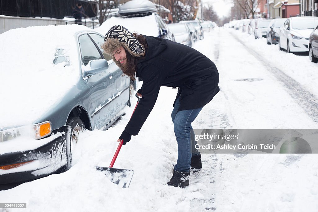 Young man clearing snow from road with shovel