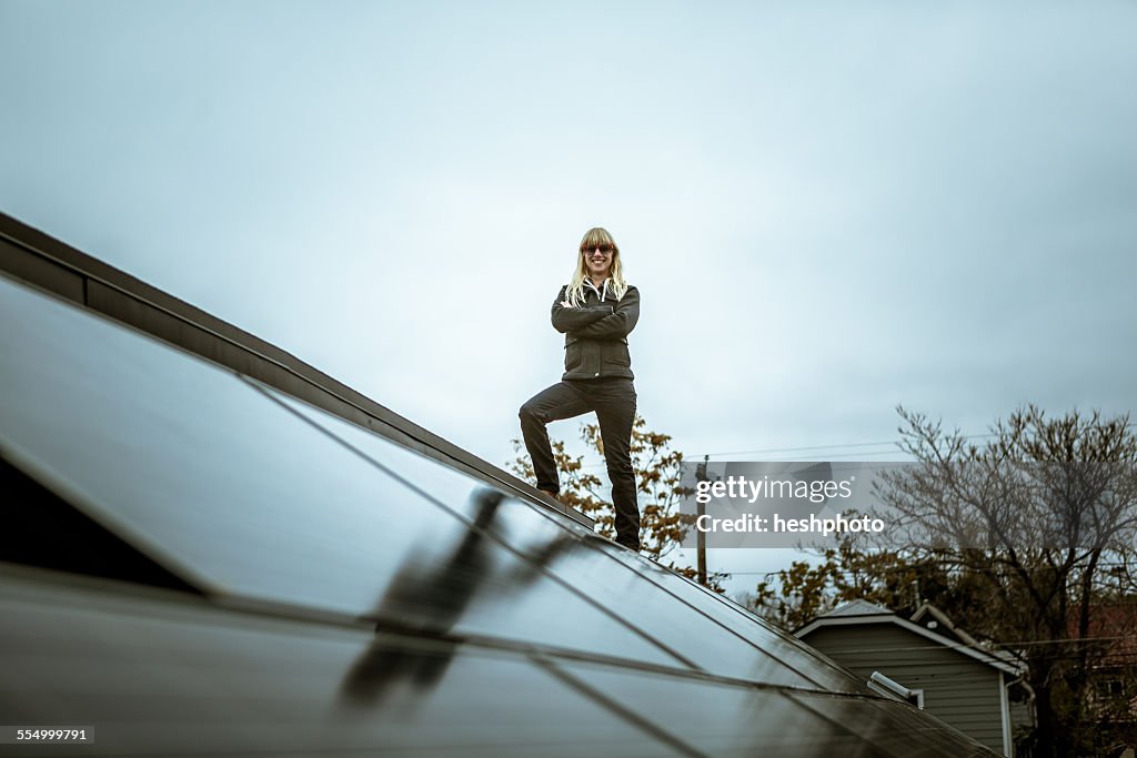 Portrait of mid adult woman standing on newly solar paneled house roof