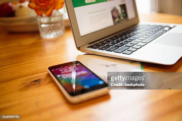 smartphone and laptop on kitchen table - heshphoto - fotografias e filmes do acervo