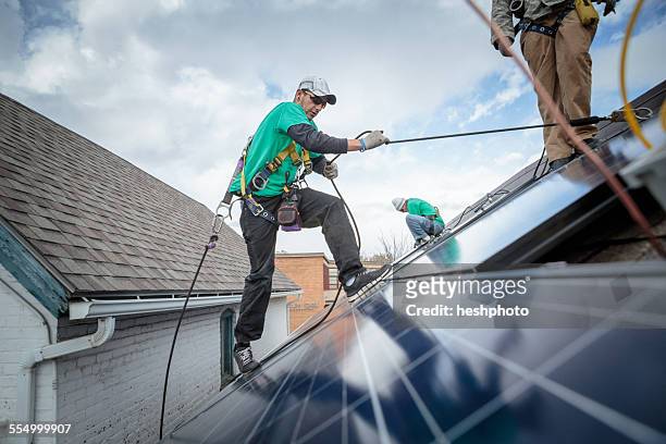 Construction crew installing solar panels on a house