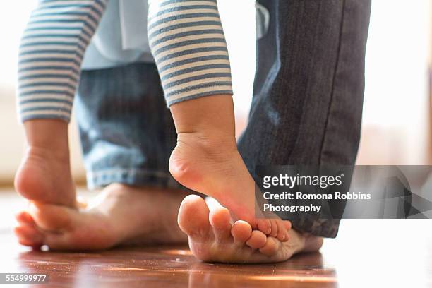 baby daughter standing on fathers feet - momentos imagens e fotografias de stock