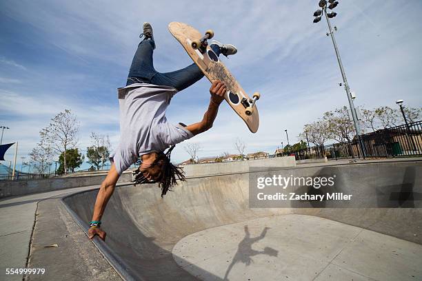 young man doing skateboard trick upside down on edge of skateboard park - inverted stock pictures, royalty-free photos & images