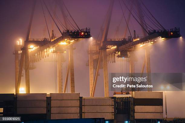 misty view of harbor cranes and stacked cargo containers at night, seattle, washington, usa - seattle port stock pictures, royalty-free photos & images