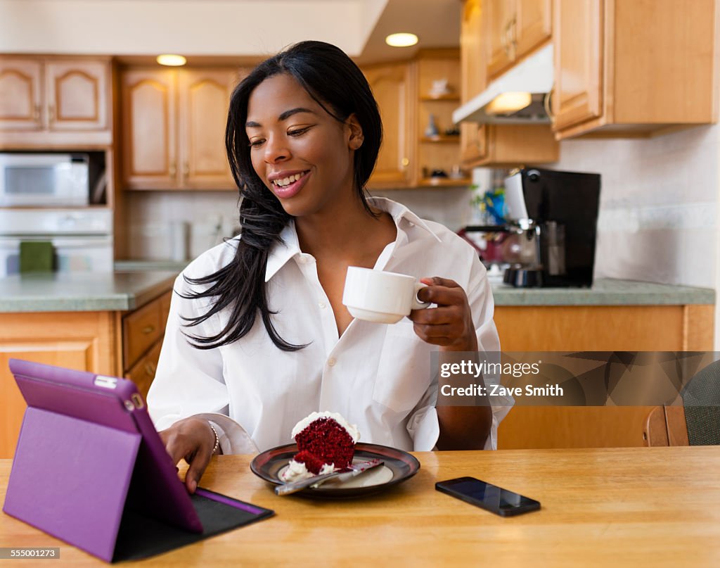 Young woman using digital tablet at kitchen table