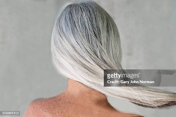 rear view of bare shouldered mature woman with long grey hair - capelli grigi foto e immagini stock