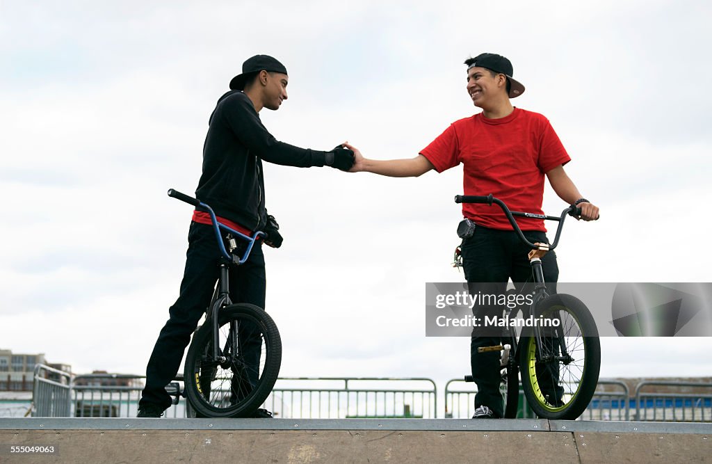 Two friends shaking hands on their BMX Bikes