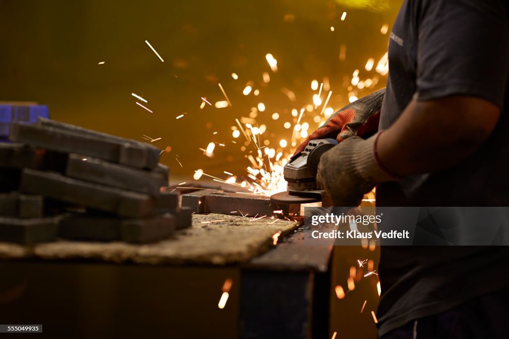 Close-up of hands polishing steel items at factory