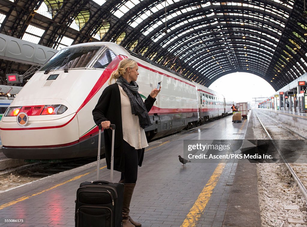 Woman checks timetable on phone, train platform