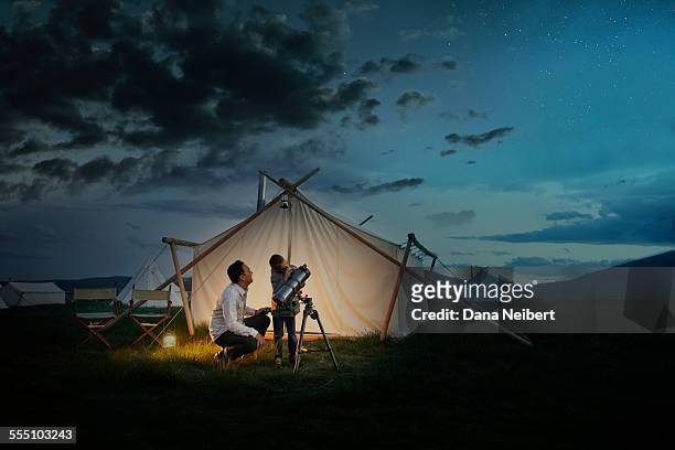 father and son looking through telescope - astronomia foto e immagini stock