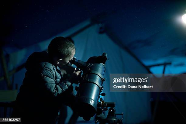 boy looking through telescope - astronomia foto e immagini stock