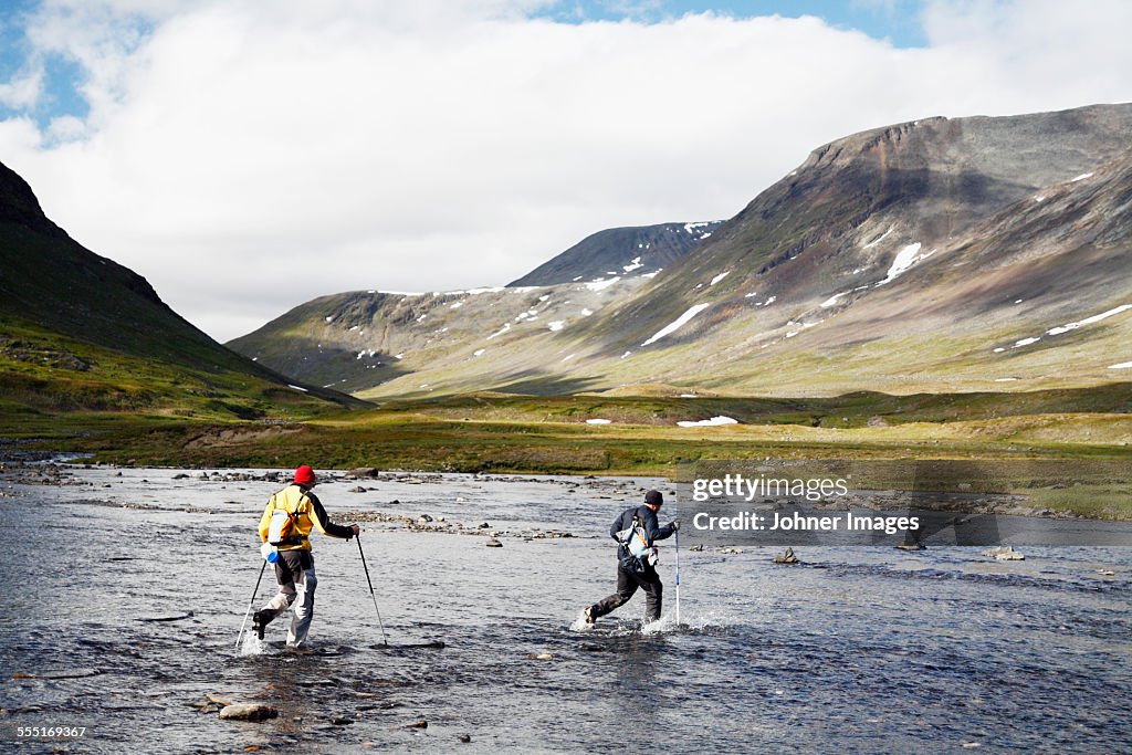 Hikers crossing mountain river