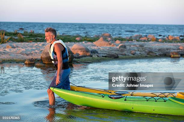 mature man pulling kayaks - oland stock-fotos und bilder