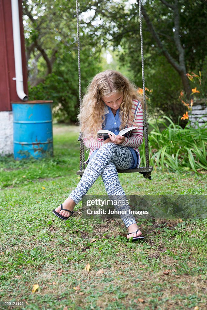 Girl on swing reading book