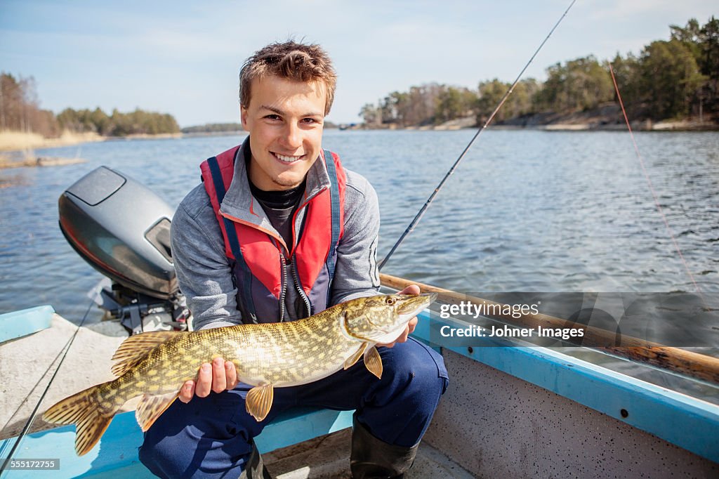 Young man holding caught fish