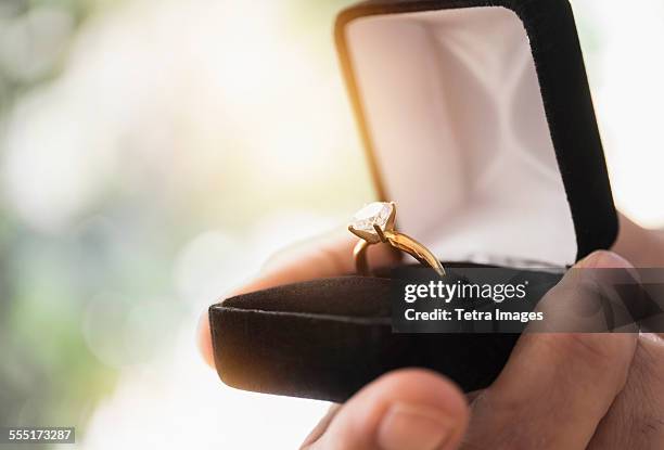 close up of mans hand holding open box with engagement ring - engagement imagens e fotografias de stock