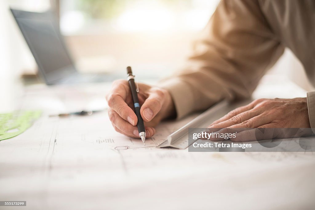 Close up of architects hands drawing on blueprint