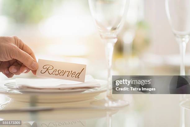 close up of mans hand setting place in restaurant - 予約済み ストックフォトと画像