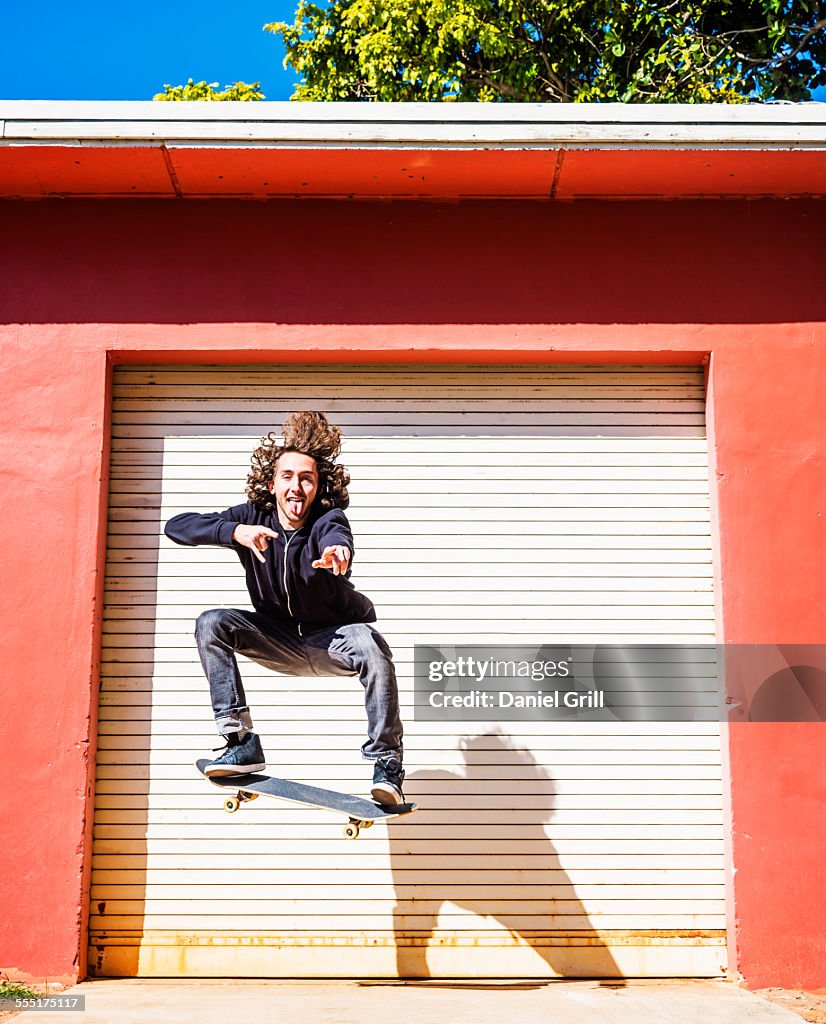 USA, Florida, West Palm Beach, Man jumping on skateboard against closed garage door